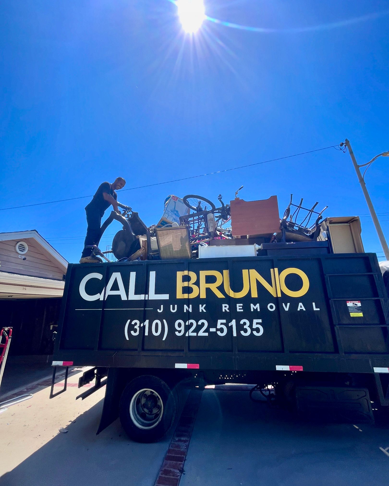 Call Bruno yellow and black junk removal dump truck parked on a Long Beach street