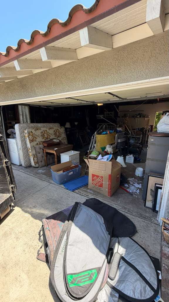 Backyard in Huntington Beach with green waste, broken patio furniture and debris before removal